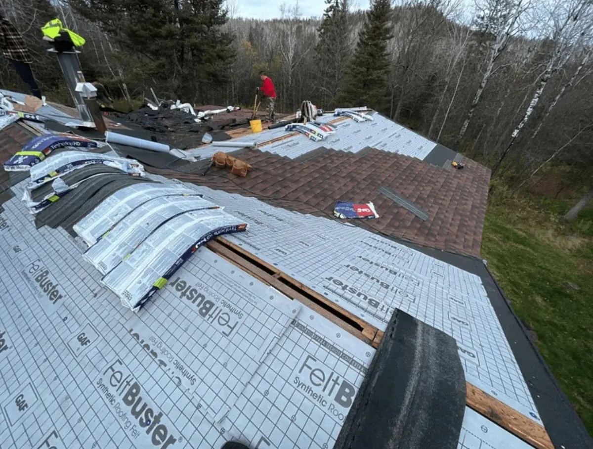 Rhino Roofing crew installing a new shingle roof on a home in the Northern Minnesota woods