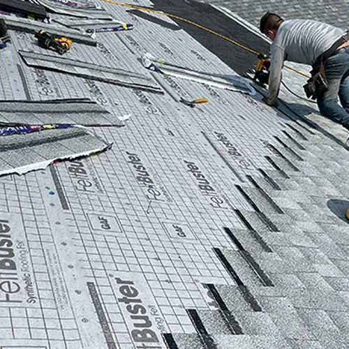Roofer fastening new shingles over synthetic underlayment