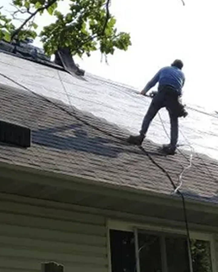 Rhino Roofing crew working on a residential roof near the tree line